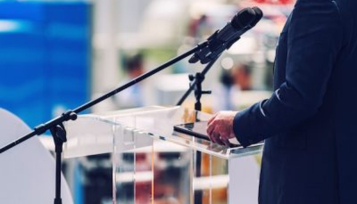 Male Speaker Standing In Front Of Microphones